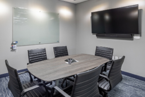 photo of small conference room equipped with video conference equipment, phone, and erasable glass white board